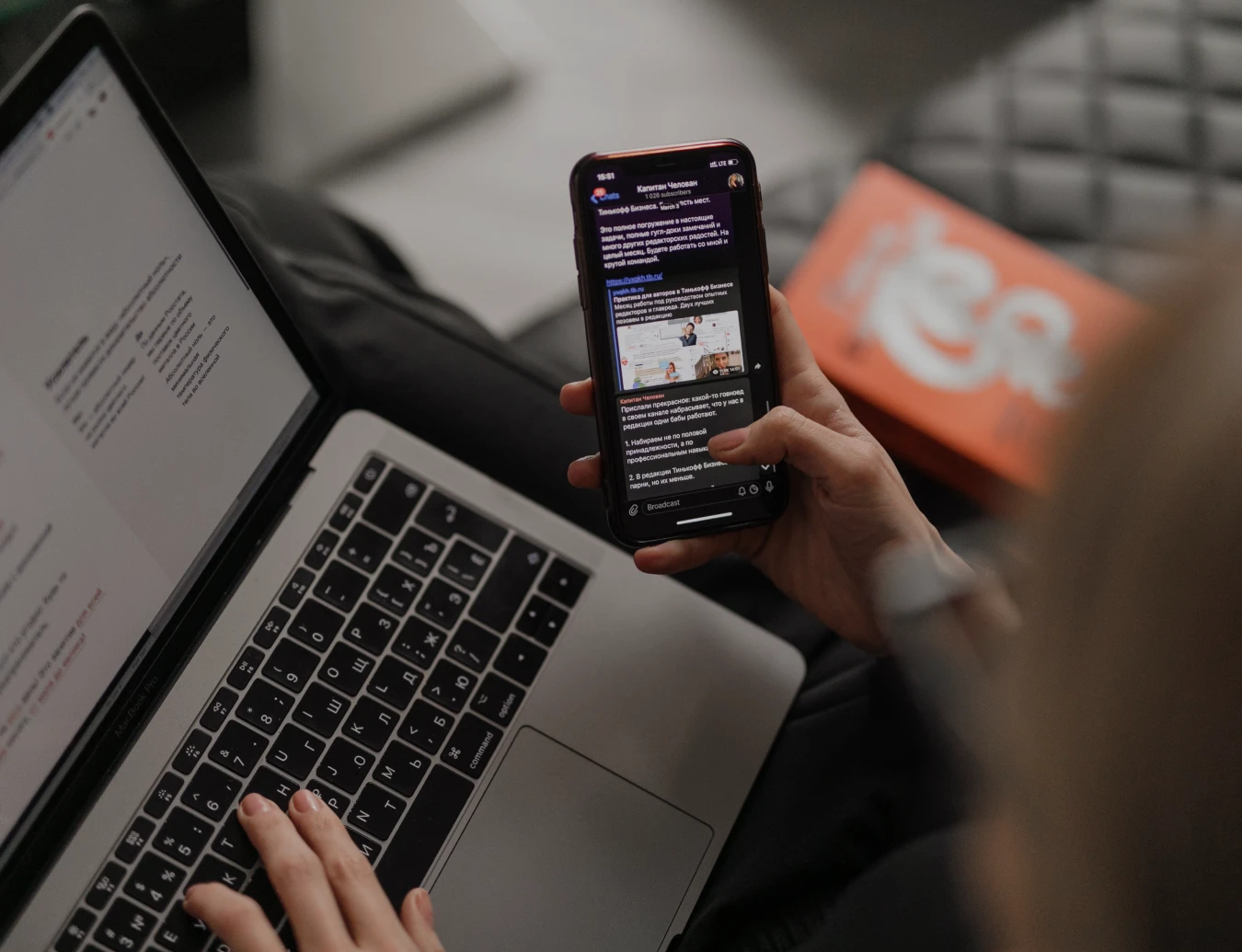 main qui tient un téléphone devant un ordinateur